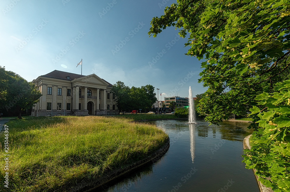 München - Die prägende Architektur des Carl Preis Palais' mit seinem Springbrunnen im Sommer mit einem Baum im Vordergrund