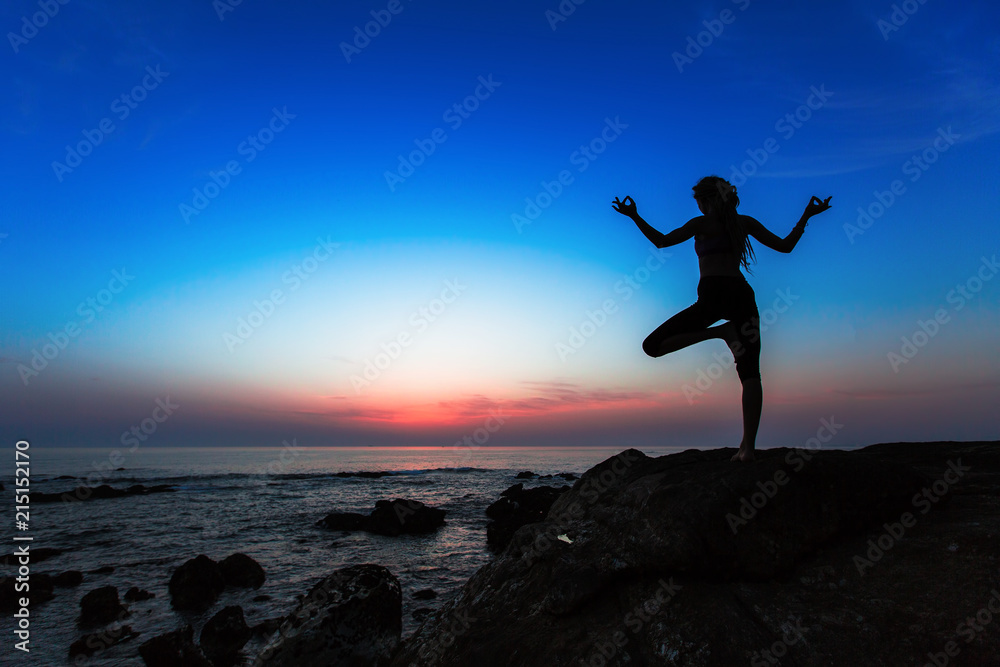 Yoga woman silhouette on the Sea during amazing sunset.