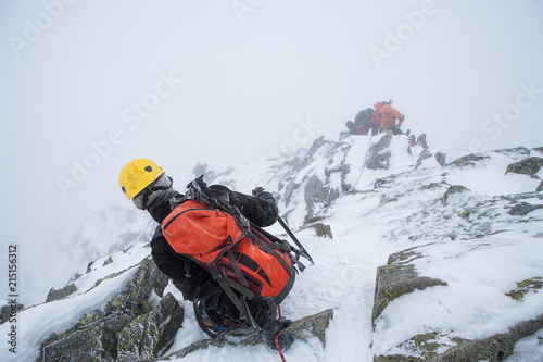 5650777 Alpinists in mountains. Team work.