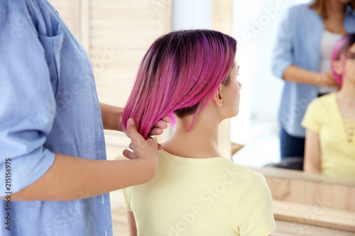 Professional hairdresser working with young woman in beauty salon. Trendy hair color