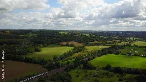 Drone aerial view over rural country side of UK with train going past. Day time wide shot. photo