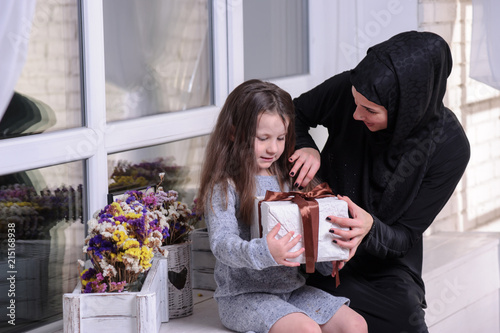 Middle Eastern mother and girl with gift box. Muslim family living lifestyle. Happy smiling Arabic parrent and child. photo