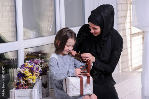 Middle Eastern mother and girl with gift box. Muslim family living lifestyle. Happy smiling Arabic parrent and child. photo