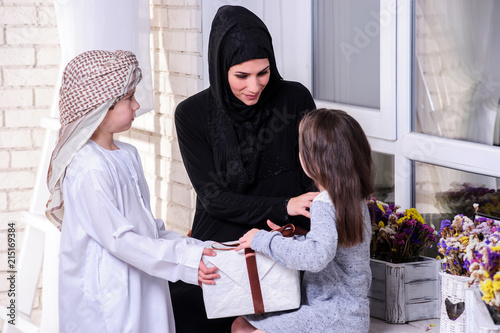 Arabic mother giving gift to her boy and girl.Muslim family. photo