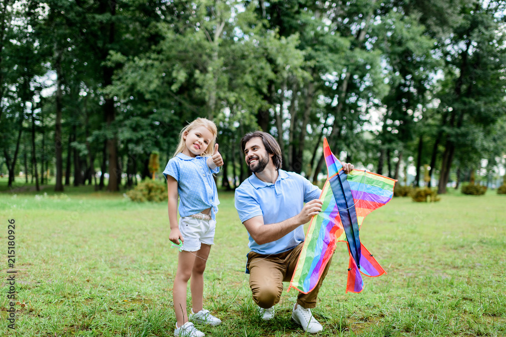 handsome happy father with kite and adorable little daughter spending time together at park handsome happy father with kite and adorable little daughter spending time together at park