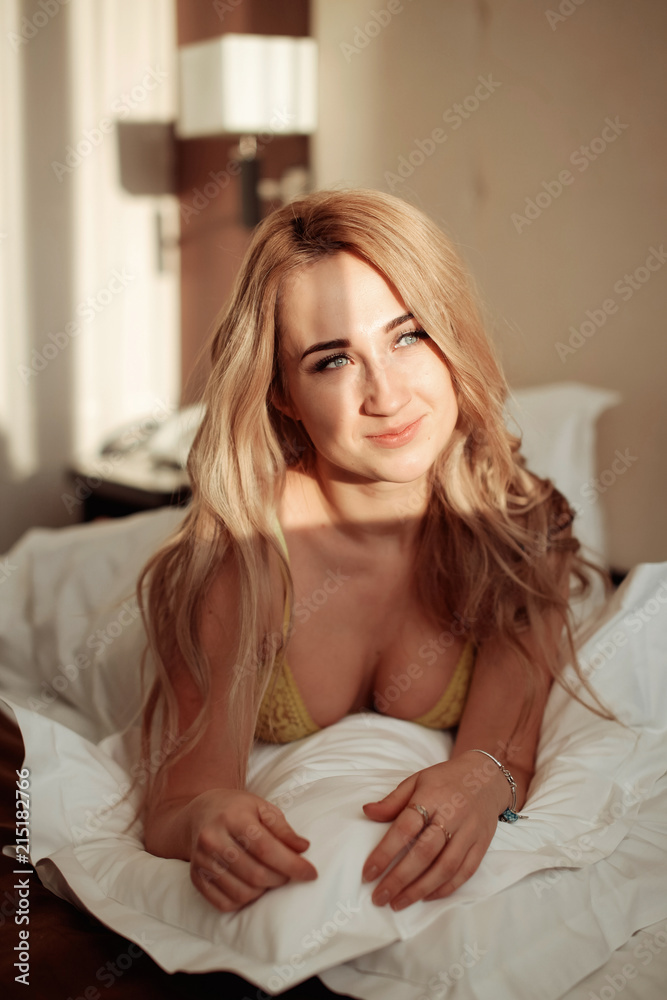 Pretty young woman on bed in modern apartment smiling after wake up Pretty young woman on bed in modern apartment smiling after wake up
