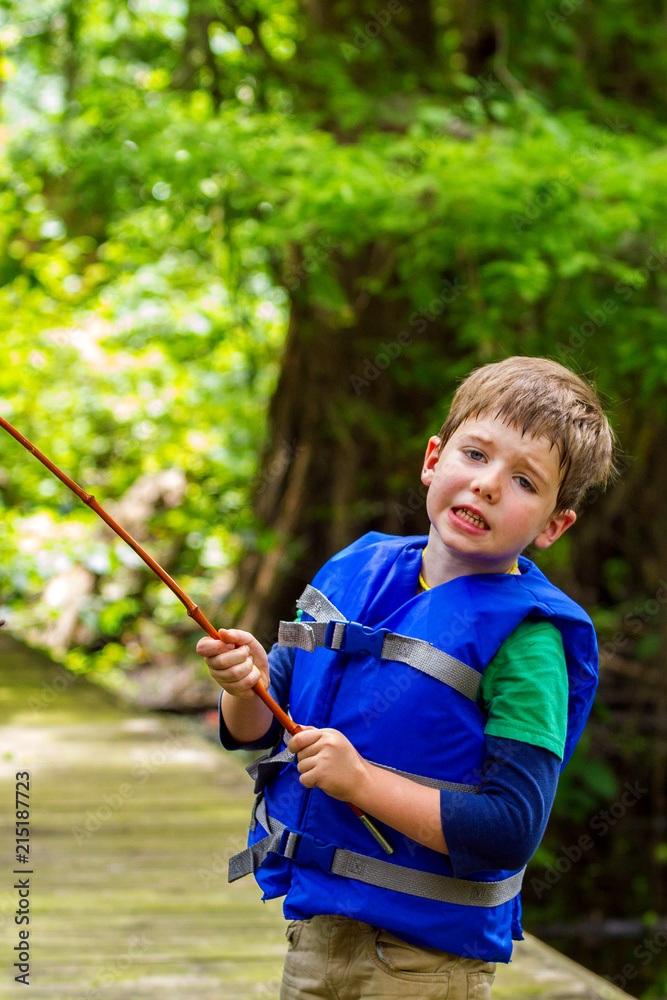 Exasperated Little Boy Looks at the Camera in Frustration Because His Fishing  Pole is Caught in a Tree Stock Photo