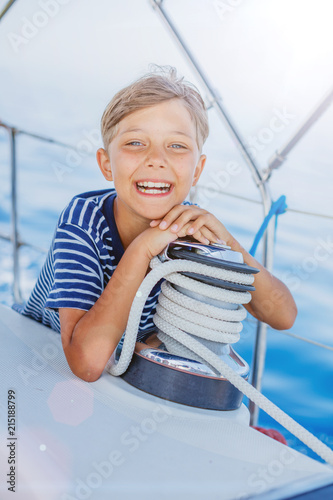 Little boy on board of sailing yacht on summer cruise. Travel adventure, yachting with child on family vacation. photo