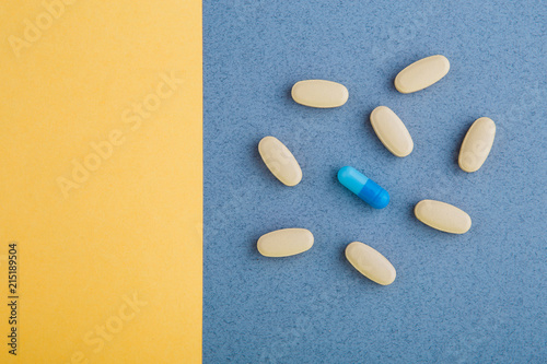 A variety of colored pills on a yellow and blue background. photo