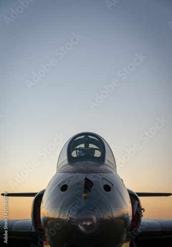 A vintage jet fighter aircraft at sunset with a dusk sky in background, vertical with upper negative space