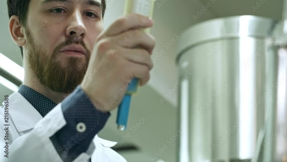 Tilt up of concentrated man in lab coat examining digital device for
