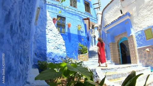 Woman with djellaba in Chefchouen street, famous blue city. Traditional moroccan architectural details photo