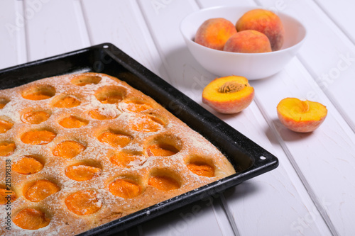 Appetizing pie from lobe peach and whole peach fruit in a white bowl