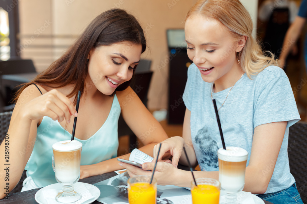 Two beautiful young girls sitting by the table in cafe Two beautiful young girls sitting by the table in cafe