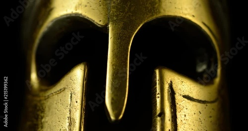 A wonderful golden Spartan helmet as part of the equipment of ancient greek soldiers. King Leonidas and his 300th The piece of metal stands against a black background