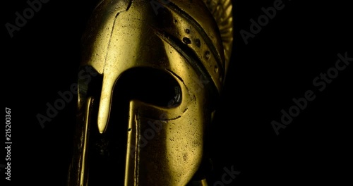 A wonderful golden Spartan helmet as part of the equipment of ancient greek soldiers. King Leonidas and his 300th The piece of metal stands against a black background