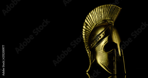 A wonderful golden Spartan helmet as part of the equipment of ancient greek soldiers. King Leonidas and his 300th The piece of metal stands against a black background photo