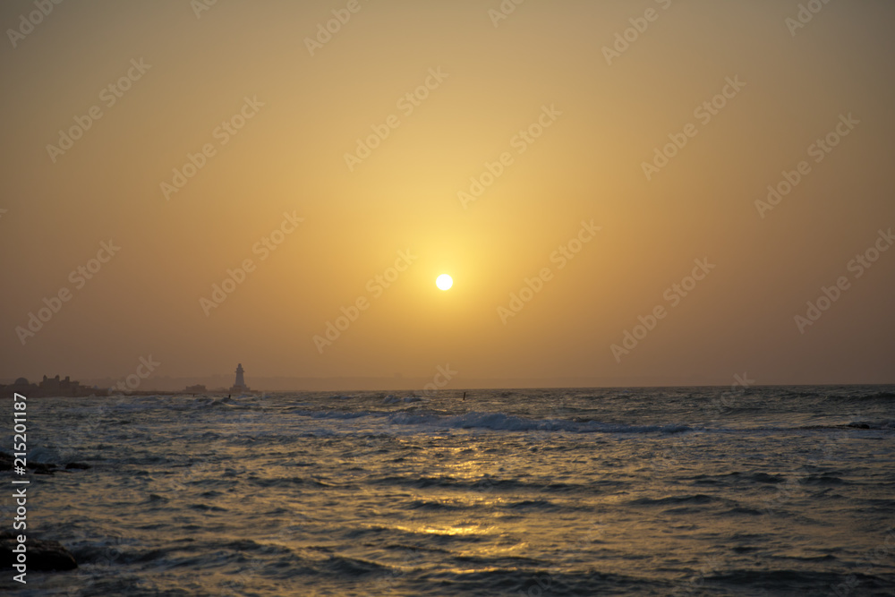 Obraz premium Beautiful sunset at the beach, amazing colors, light beam shining through the cloudscape. Azerbaijan sea and beach . The sound of the sea waves is coming . The fisherman fishes in the sea .