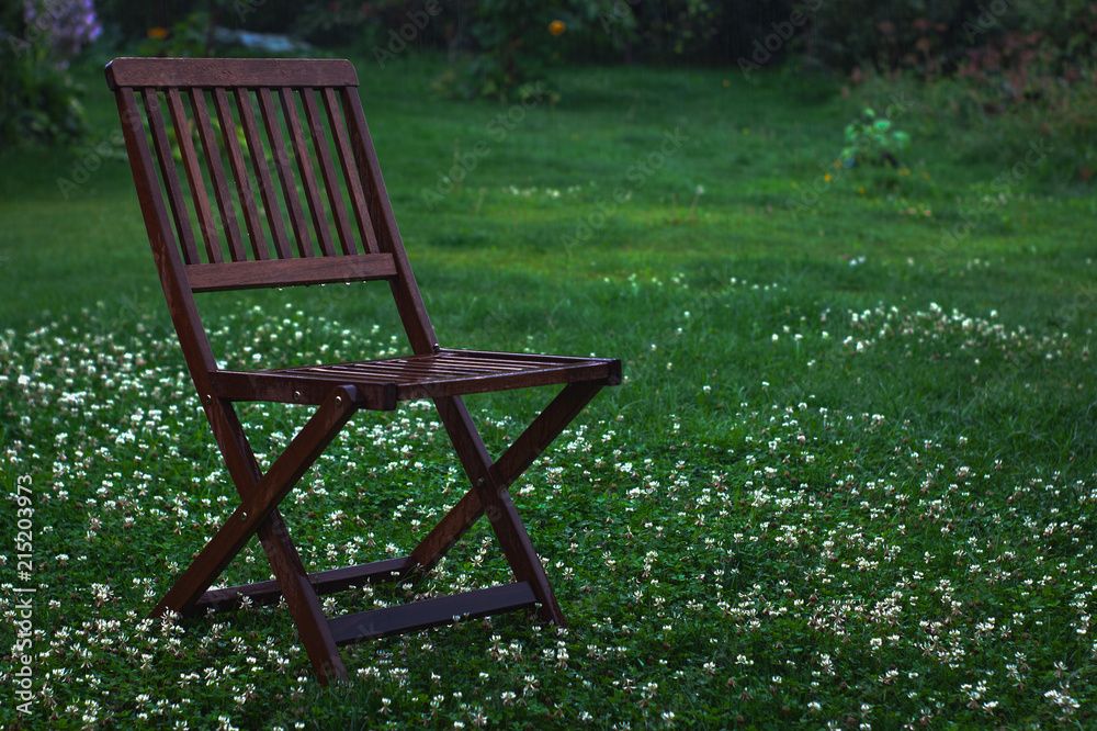 Wet wooden brown chair on grass after raining. Wet wooden brown chair on grass after raining.