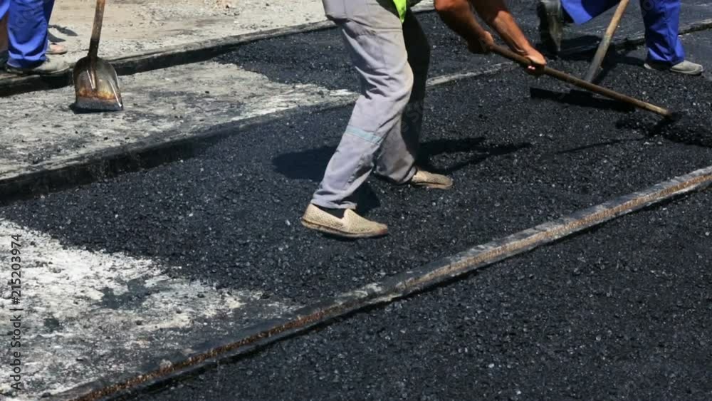 Workers construct asphalt road and railroad lines Workers construct asphalt road and railroad lines