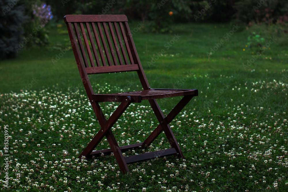 Wet wooden brown chair on grass after raining. Wet wooden brown chair on grass after raining.