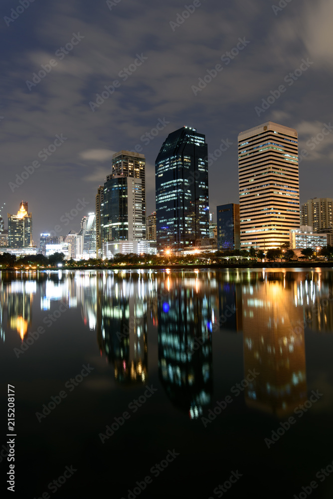 Modern buildings of Benchakitti Park with lights reflection in night city
