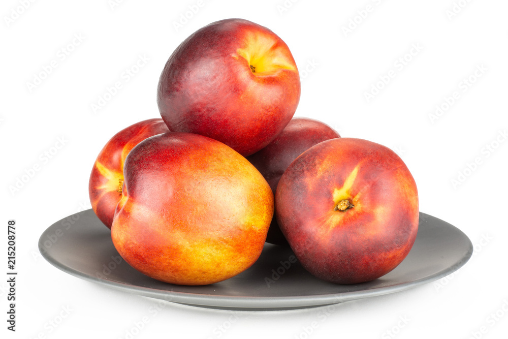 Lot of whole ripe deep red nectarine heap on a grey ceramic plate isolated on white