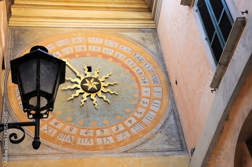 Antique renaissance clock in an alley in the city with old street lamp. Brescia, Italy.