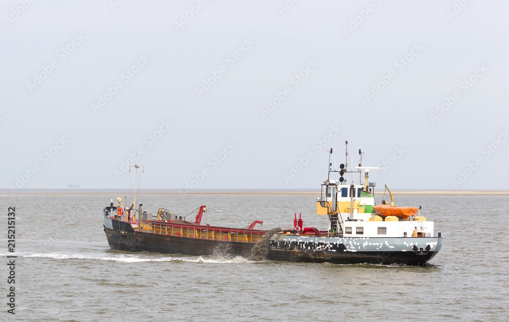 Sand dredging boat drawing away from coast shoreline to pump sand Sand dredging boat drawing away from coast shoreline to pump sand