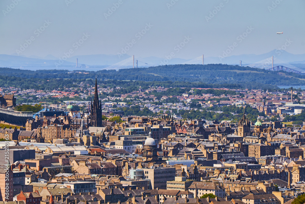 Edinburgh cityscape with churches, Forth bridge and Queensferry Bridge in the background.