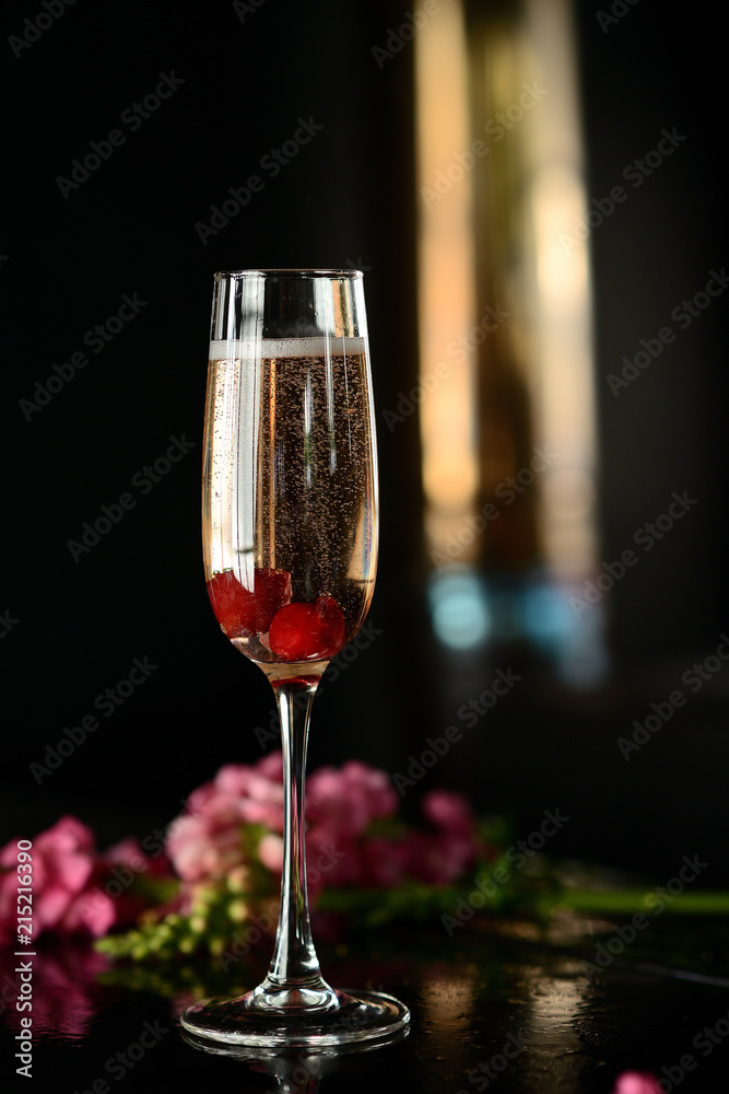 Champagne in a glass with a red berry on a black table Champagne in a glass with a red berry on a black table