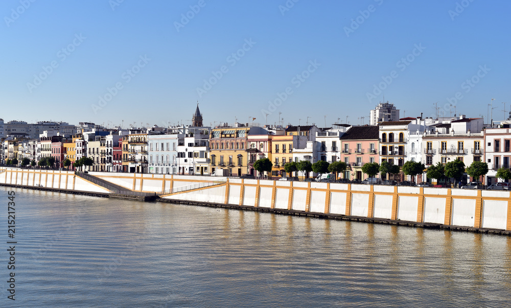 Colorful houses underneath a blue sky by the Guadalquivir river in Seville, Spain