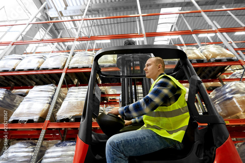 Obraz na plátně logistic business, shipment and people concept - male worker driving forklift lo