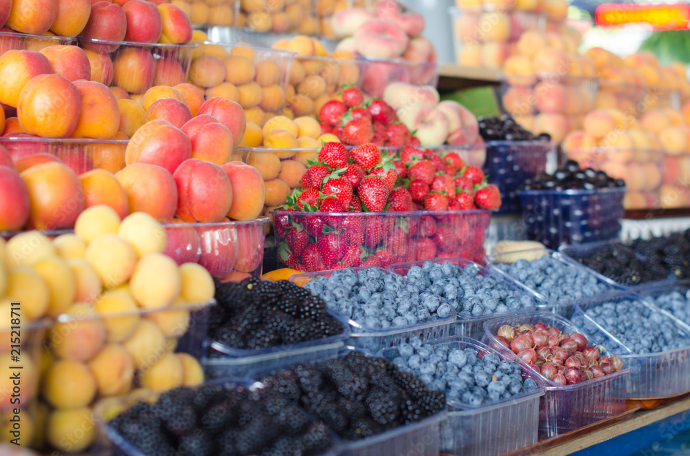 Containers with different ripe berries and fruit at market Containers with different ripe berries and fruit at market