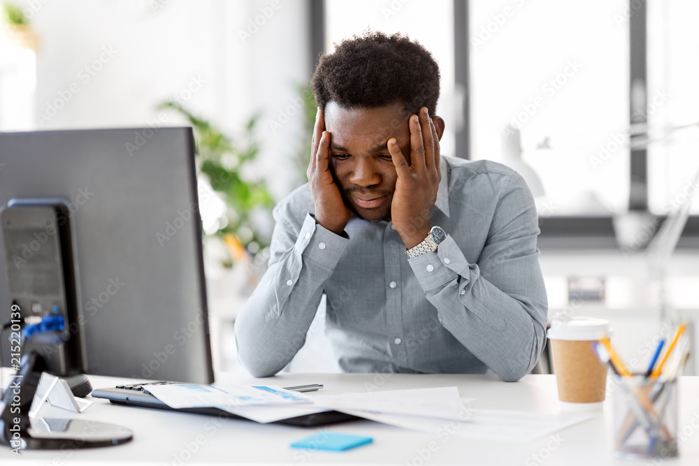 business, people, deadline and technology concept - stressed african american businessman with papers and computer working computer at office business, people, deadline and technology concept - stressed african american businessman with papers and computer working computer at office