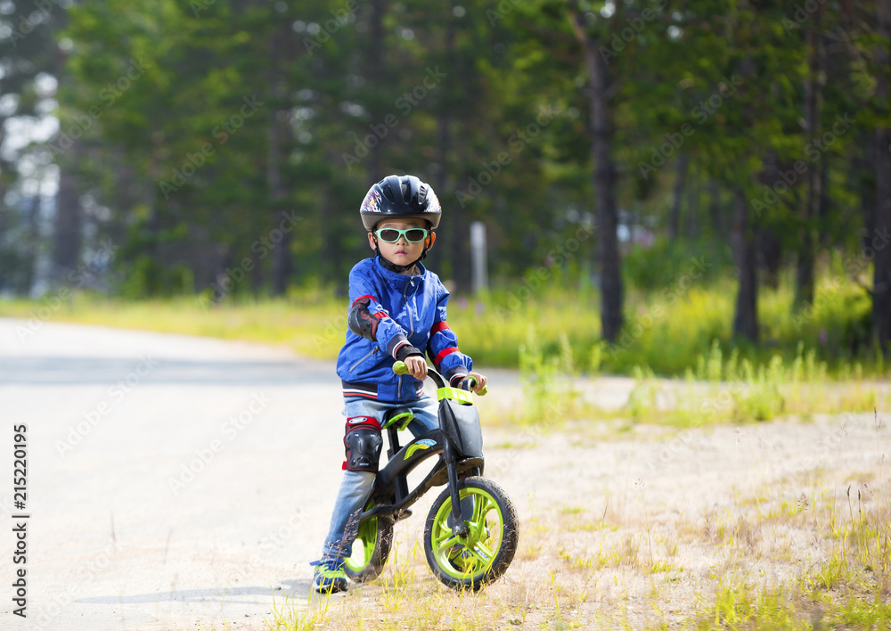 Happy boy having fun riding a bicycle with glasses, helmet, in defense Happy boy having fun riding a bicycle with glasses, helmet, in defense