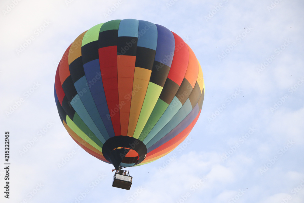 Fototapeta premium colorful hot air balloon against blue sky. hot air balloon is flying in white clouds. beautiful flying on hot air balloon