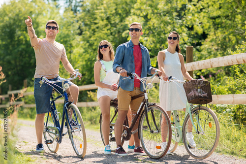 people, leisure and lifestyle concept - happy young friends riding fixed gear bicycles in summer