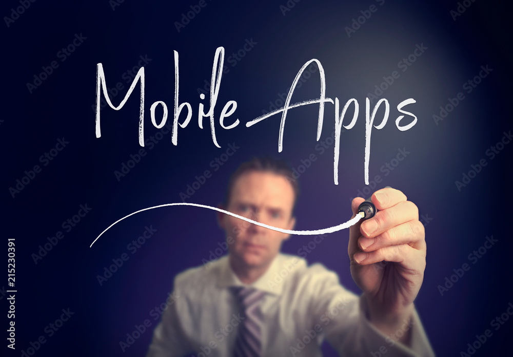 A businessman writing a mobile apps concept with a white pen on a clear screen. A businessman writing a mobile apps concept with a white pen on a clear screen.