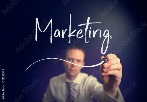 A businessman writing a marketing concept with a white pen on a clear screen.
