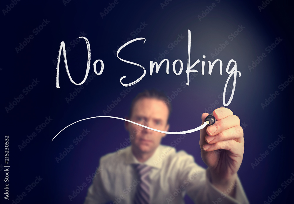 A businessman writing a no smoking concept with a white pen on a clear screen. A businessman writing a no smoking concept with a white pen on a clear screen.