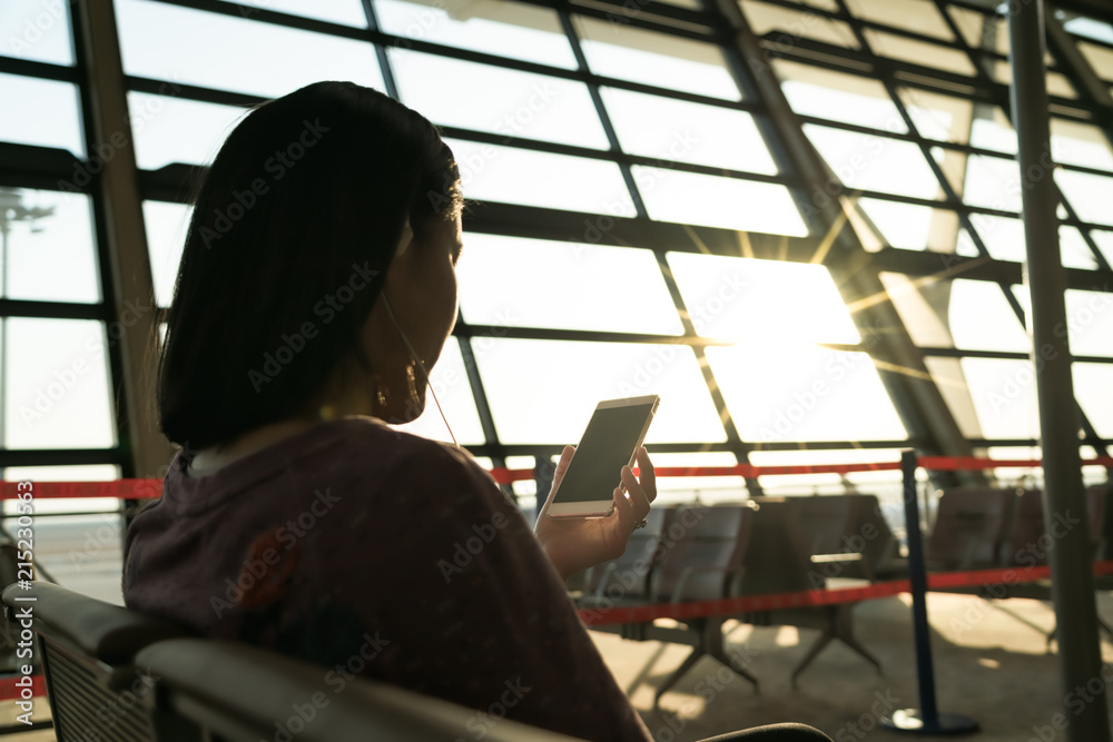 Fototapeta premium young women searching information while waiting for flying at airport window