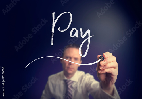 A businessman writing a pay concept with a white pen on a clear screen.