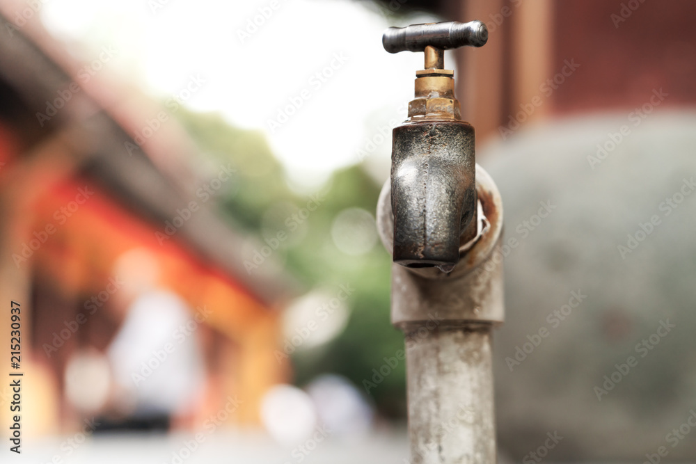 a bronze metallic faucet with water drop on blurred background
