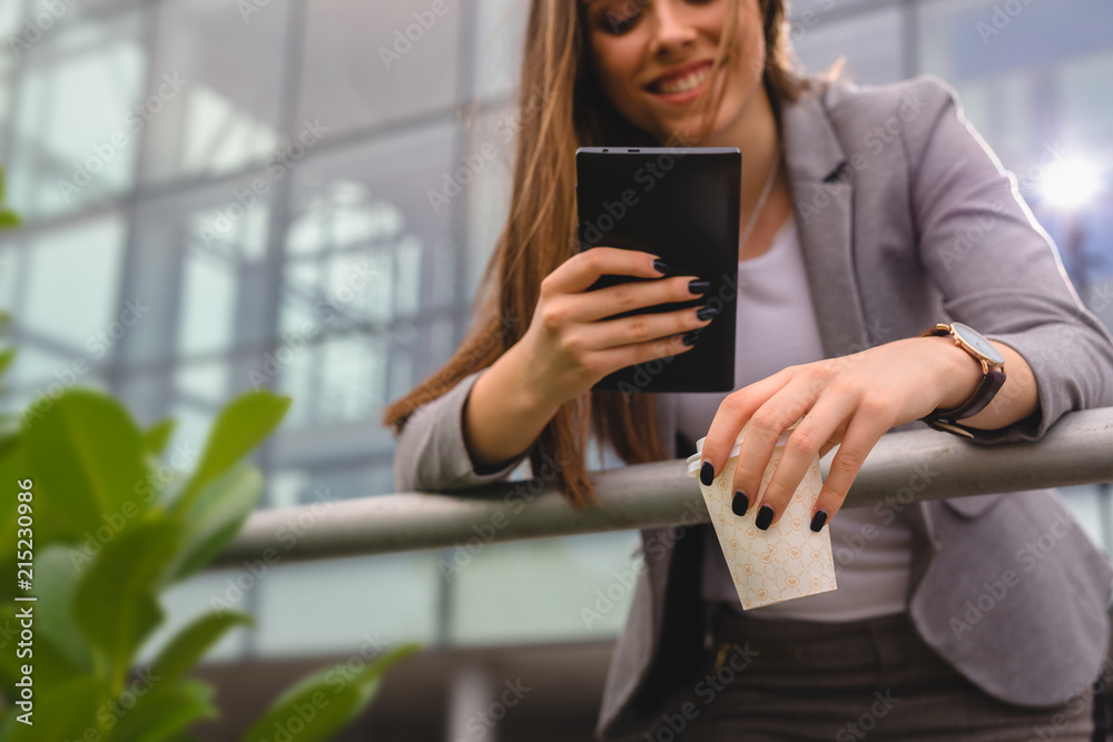 Business woman drinking coffee and using tablet outdoor