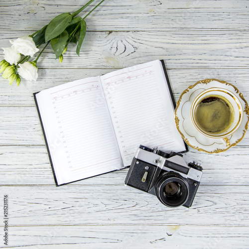 white ustom, diary, antique camera and cup of coffee and saucer on a light background, flat lay photo