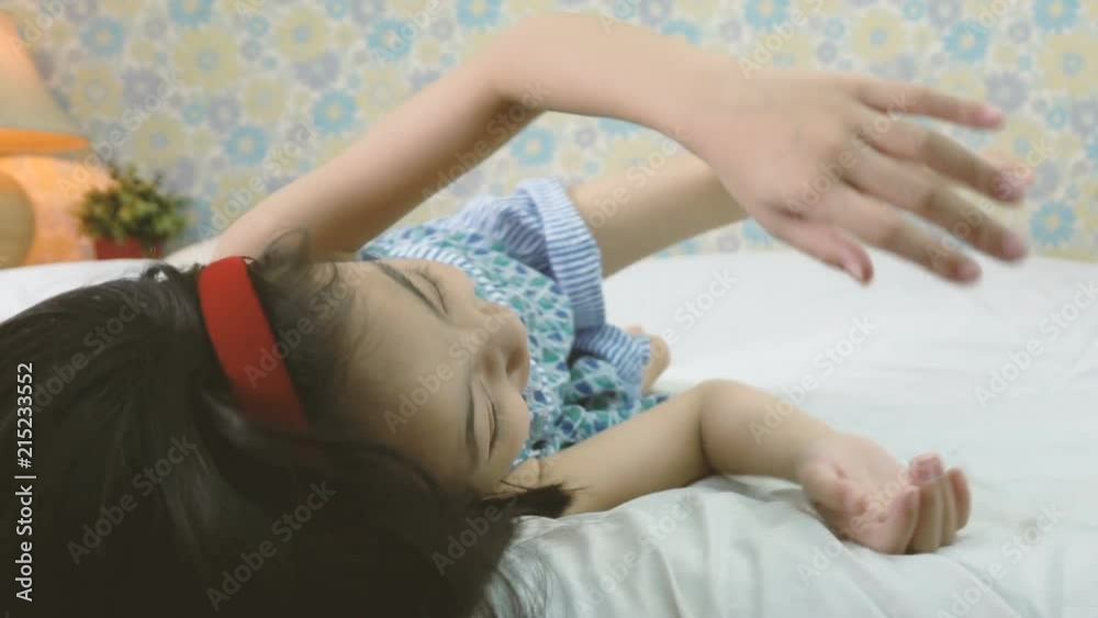 Slow motion shot of happy little girl lying in bed smiling and laughing Slow motion shot of happy little girl lying in bed smiling and laughing