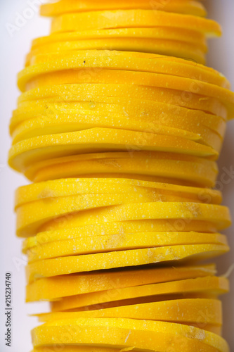 Top view close up of sliced summer yellow squash on white background