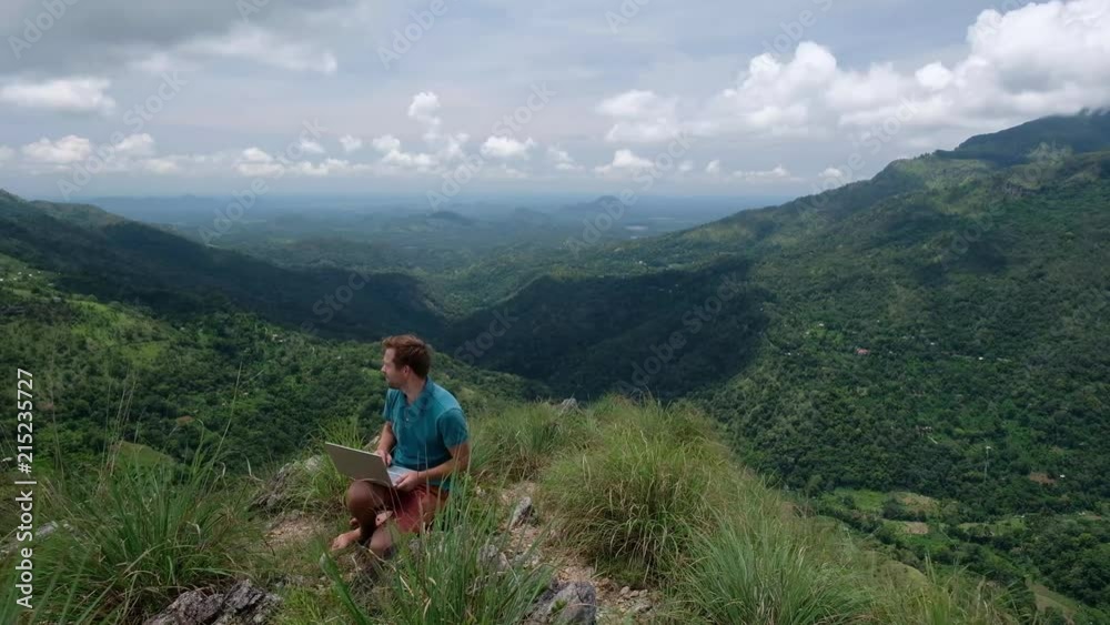 European man with laptop working on the hill. Concept of having internet connection in every place of world