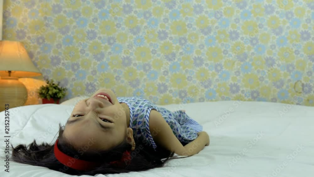 Happy little girl lying in bed smiling and laughing